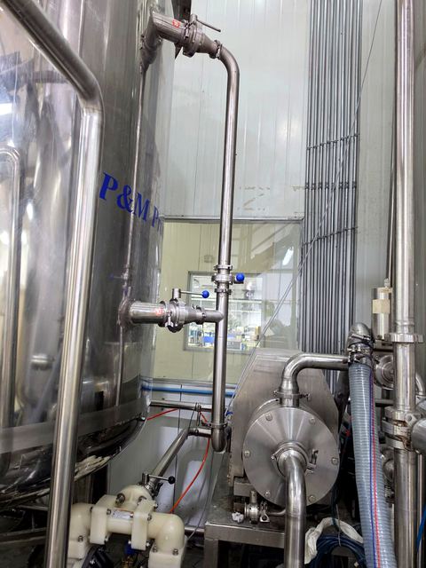 Instalación de piping de acero inoxidable y bomba en sala de fabricación